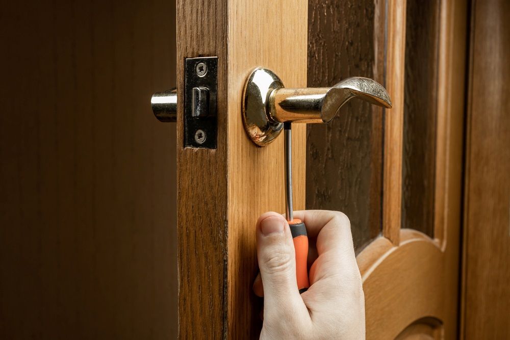 A Person is Fixing a Door Handle With a Screwdriver — Coffs City Lockmart Pty Ltd in Nambucca Heads, NSW