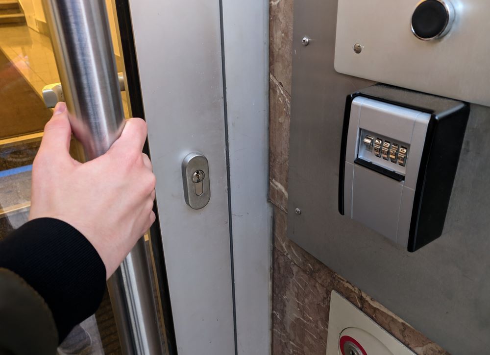 A Person is Opening a Door Next to a Key Box — Coffs City Lockmart Pty Ltd in Woolgoolga, NSW