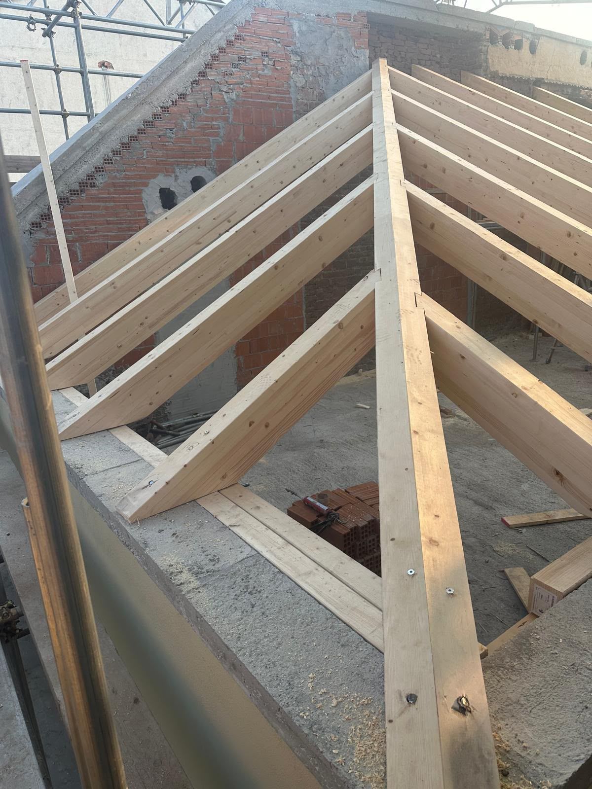 Capriate in legno in fase di costruzione su un edificio in mattoni, viste dall'alto.