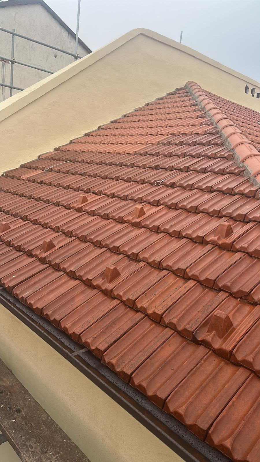 Tetto in tegole di argilla rossa su un edificio beige, visto dall'alto.