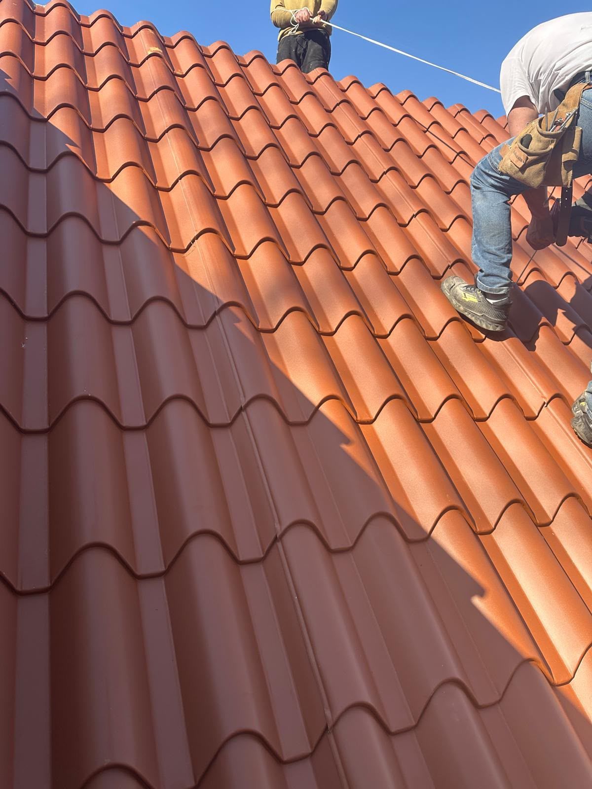 Operai che installano tegole di terracotta su un tetto inclinato