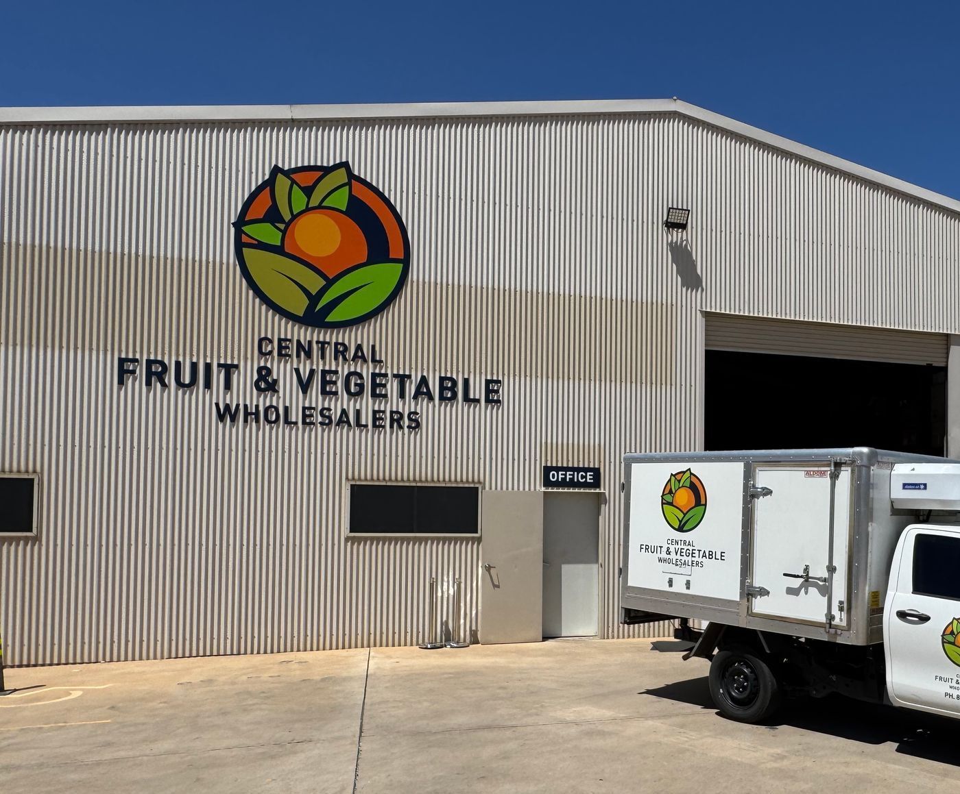 A truck is parked in front of a building that says central fruit & vegetable wholesalers
