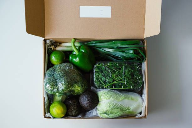 A cardboard box filled with a variety of green vegetables.