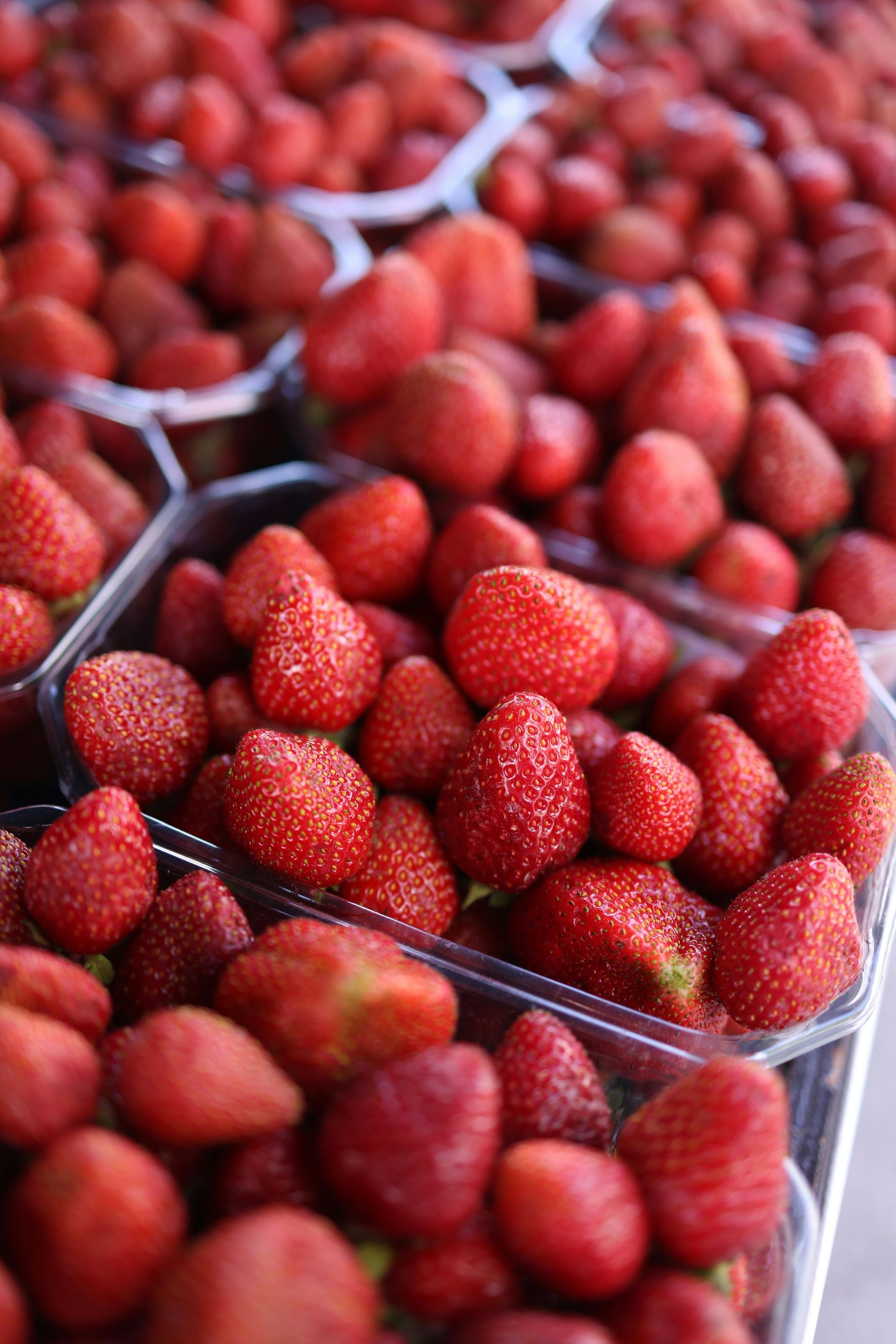 A bunch of strawberries in plastic containers on a table.