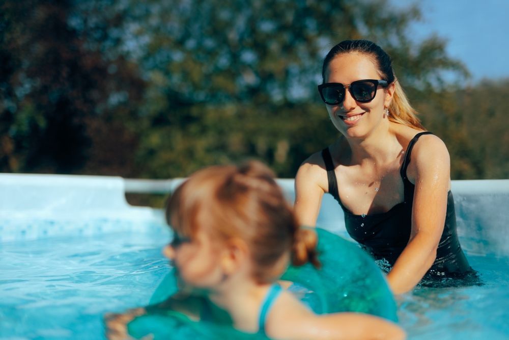Woman supervising her child as her child learns how to swim in a swimming pool.