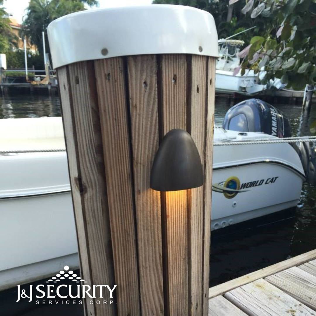 Wooden dock post with a small light; boat in background on water.