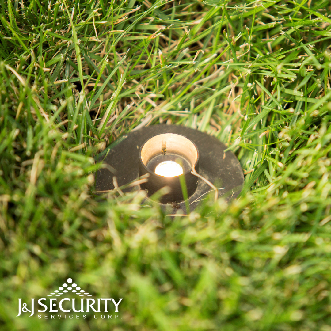 A ground-level spotlight in green grass, emitting bright light.