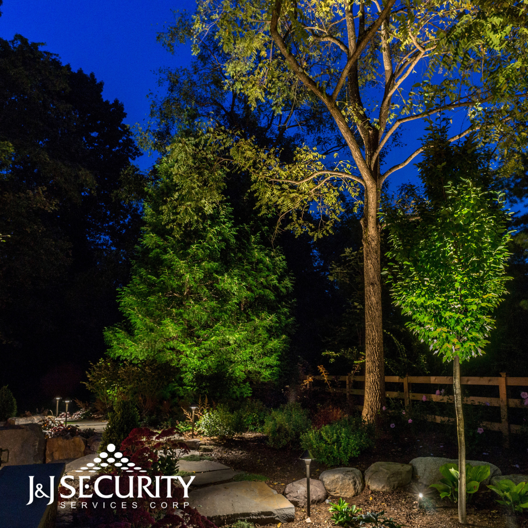 Nighttime landscape with illuminated trees, rock border, and path, with