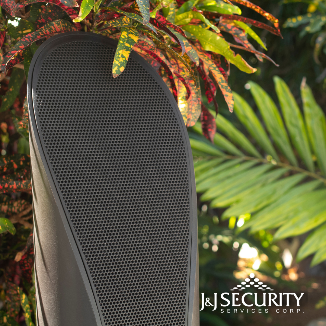 Close-up of a black boot sole with textured grip, set against a backdrop of colorful foliage; J&J Security logo in corner.