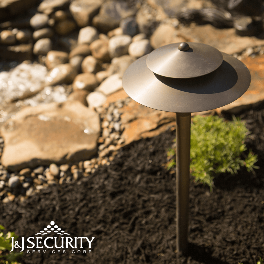 Bronze landscape uplight in a garden bed with rocks.