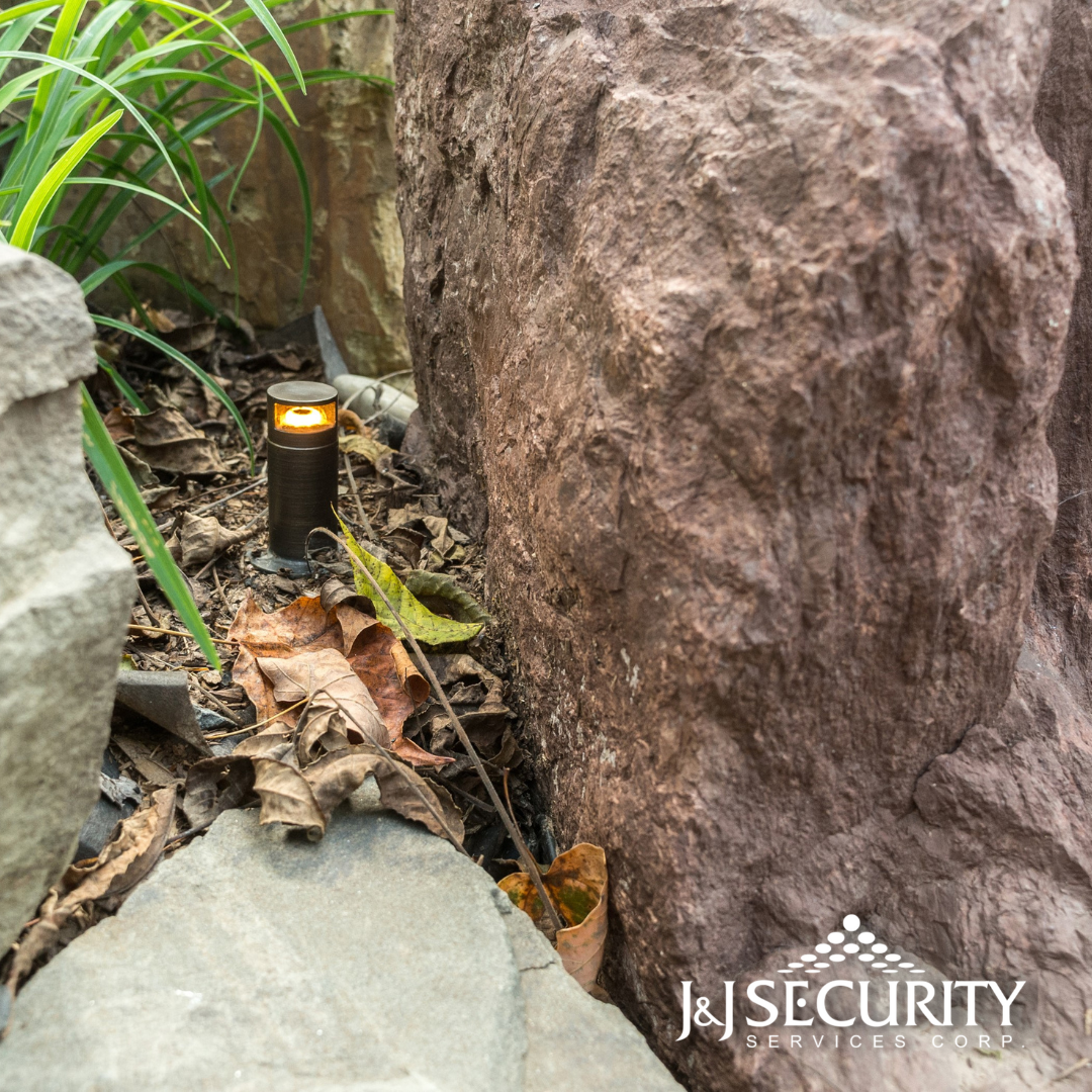 Bronze landscape light illuminates rock garden with foliage.