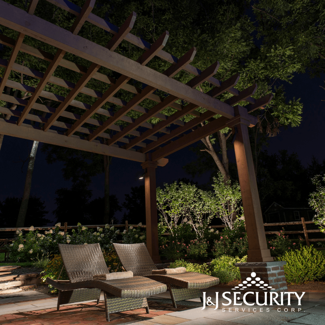 Wooden pergola over two wicker chairs in a lit garden at night.
