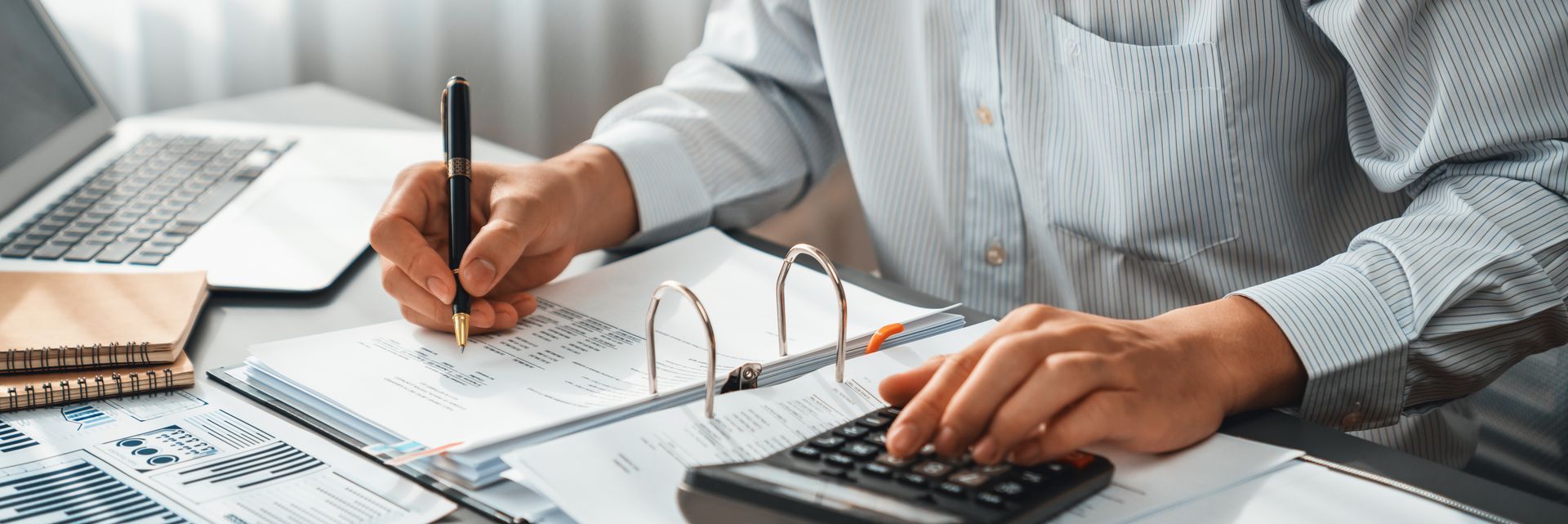 Cropped view of a tax accountant calculating a budget with a calculator on his office desk. 