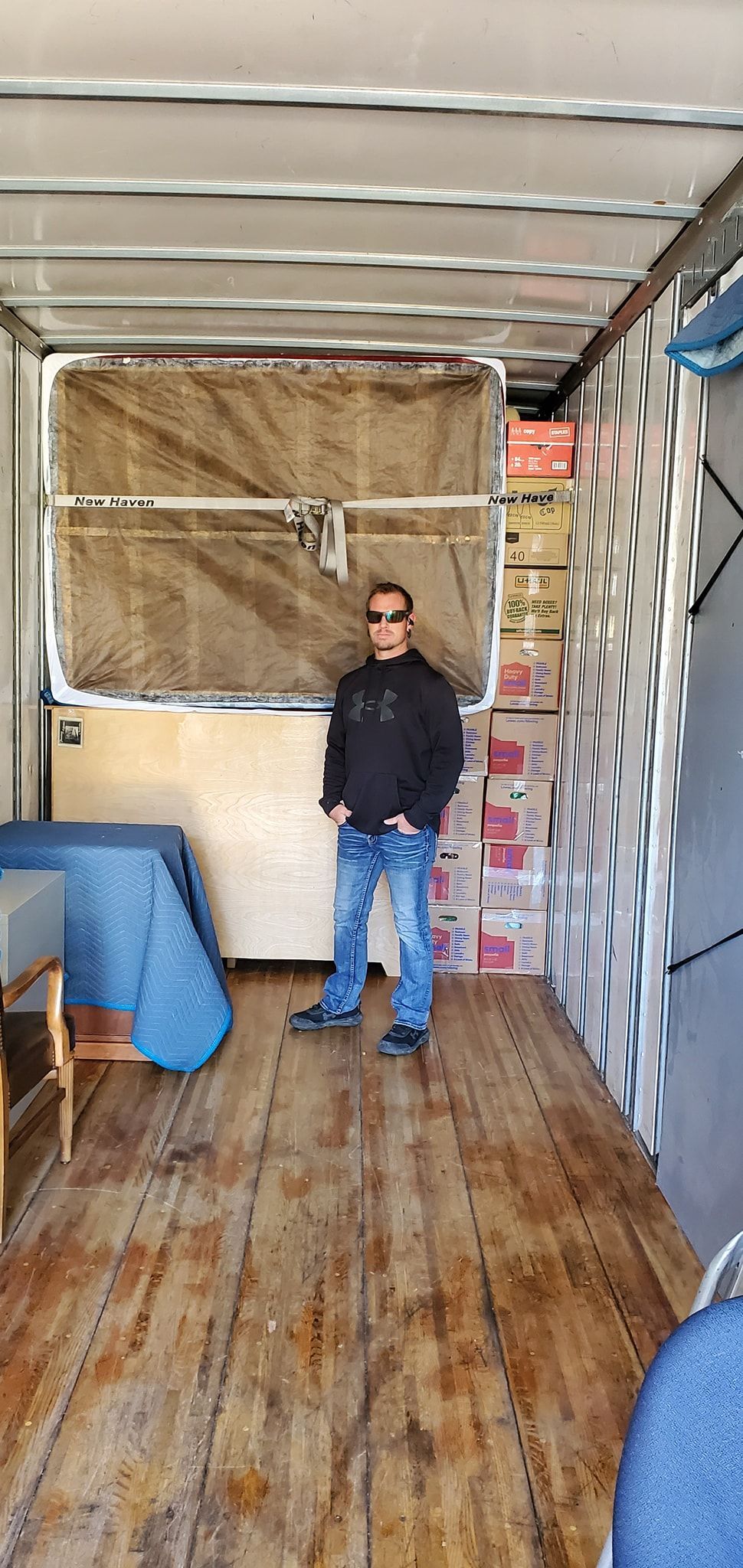 Man standing inside a cargo trailer with wooden floor and packed side walls