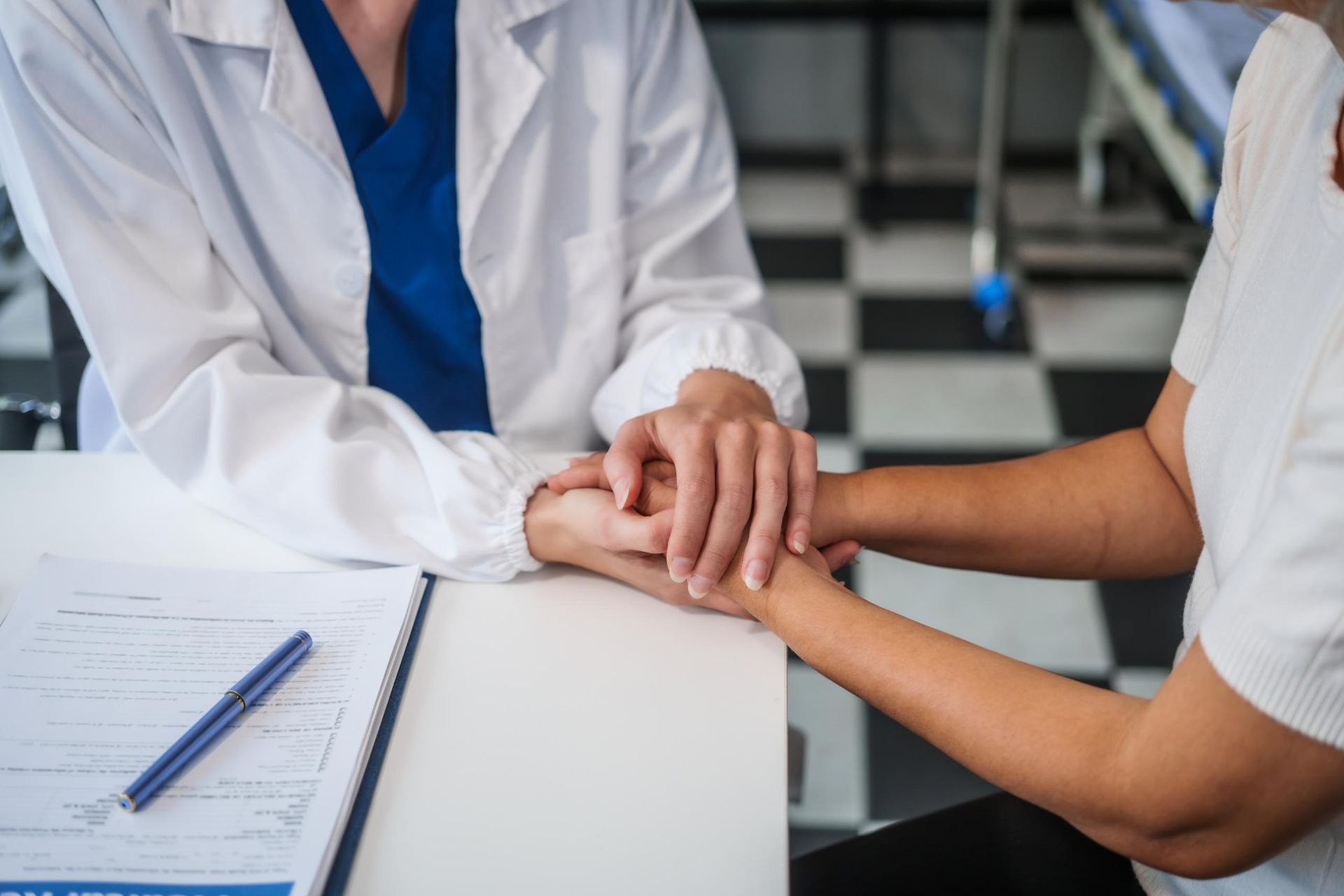 Doctor is Holding the Hand of a Patient at a Table — Mullumbimby Comprehensive Health Centre in Mullumbimby, NSW