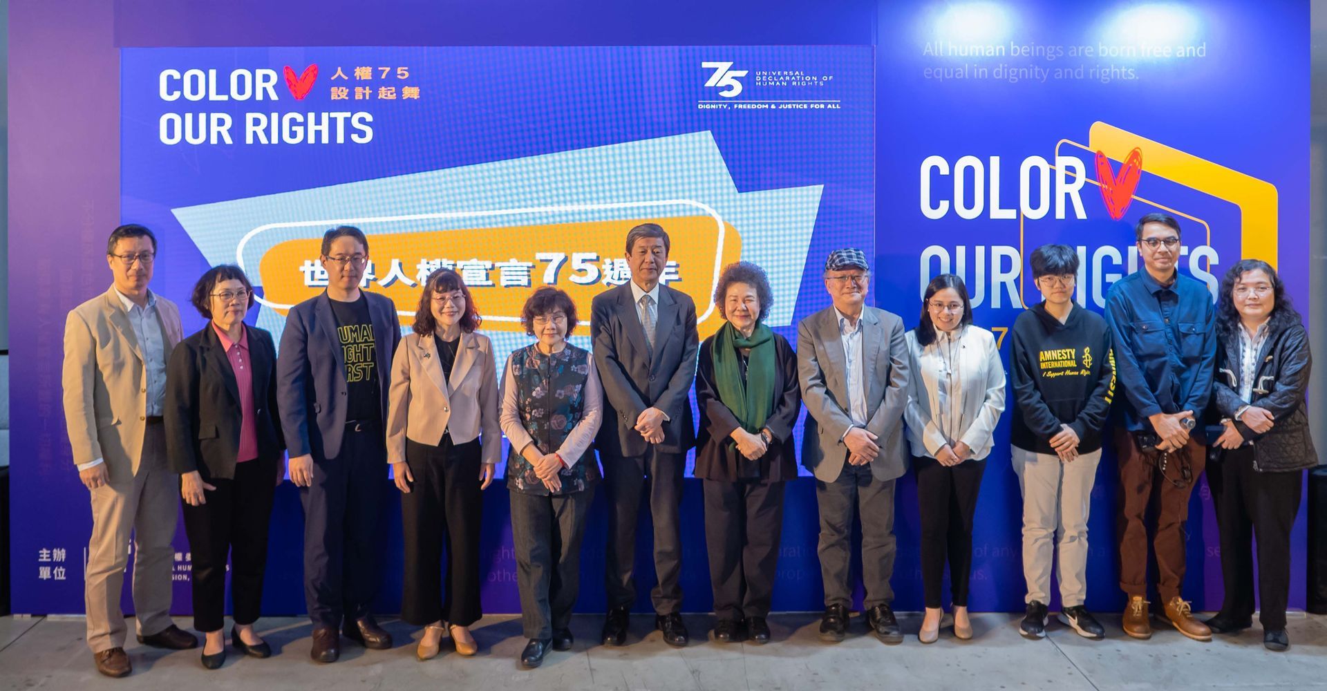 Group of people standing in front of a blue backdrop with event branding that reads 