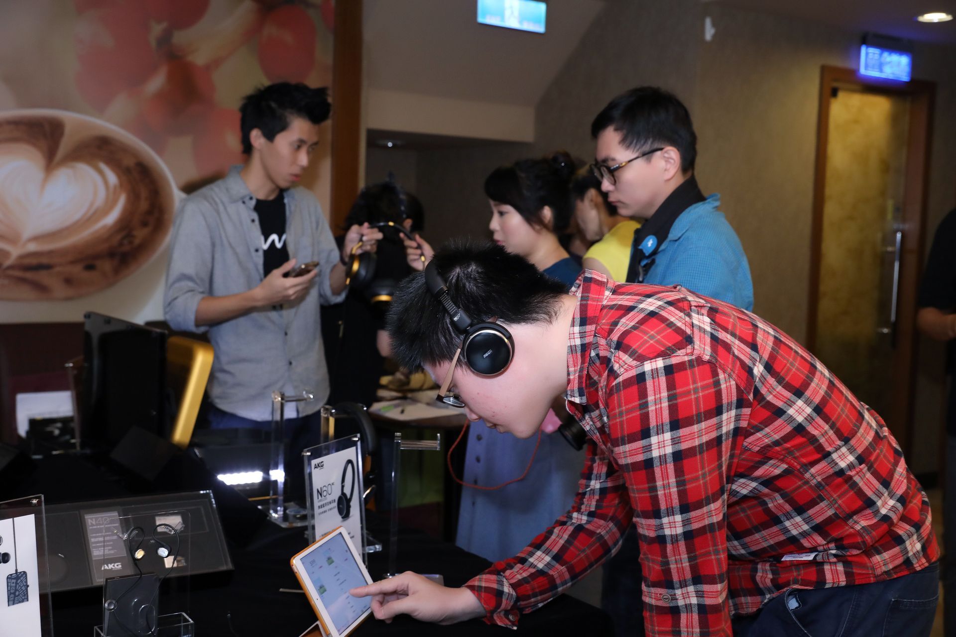 People trying headphones at a display in a store. One man touches a tablet.