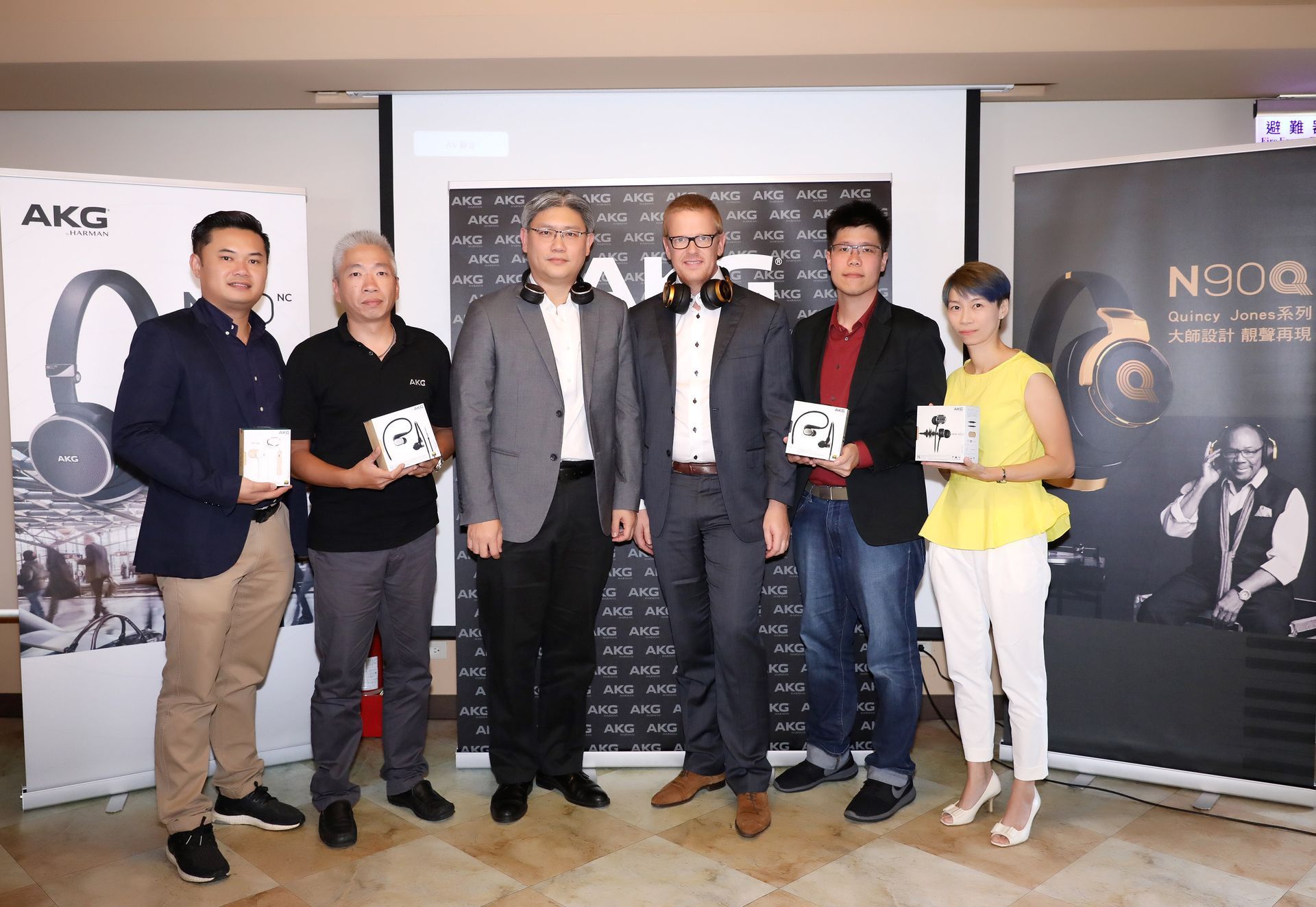 Group of people holding headphones at an AKG product launch event.