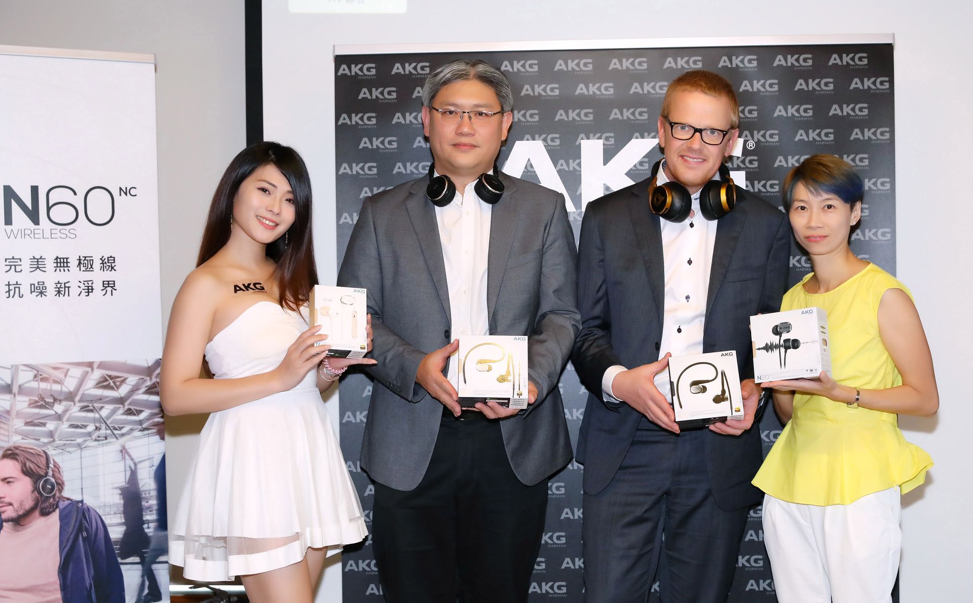 Four people at a product launch; two men and two women hold headphone boxes. AKG backdrop.