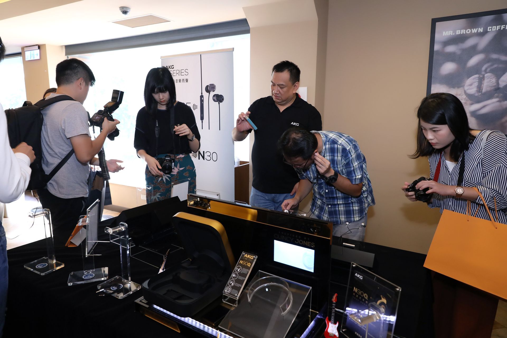 People at a product demonstration, examining and photographing items on a display table.