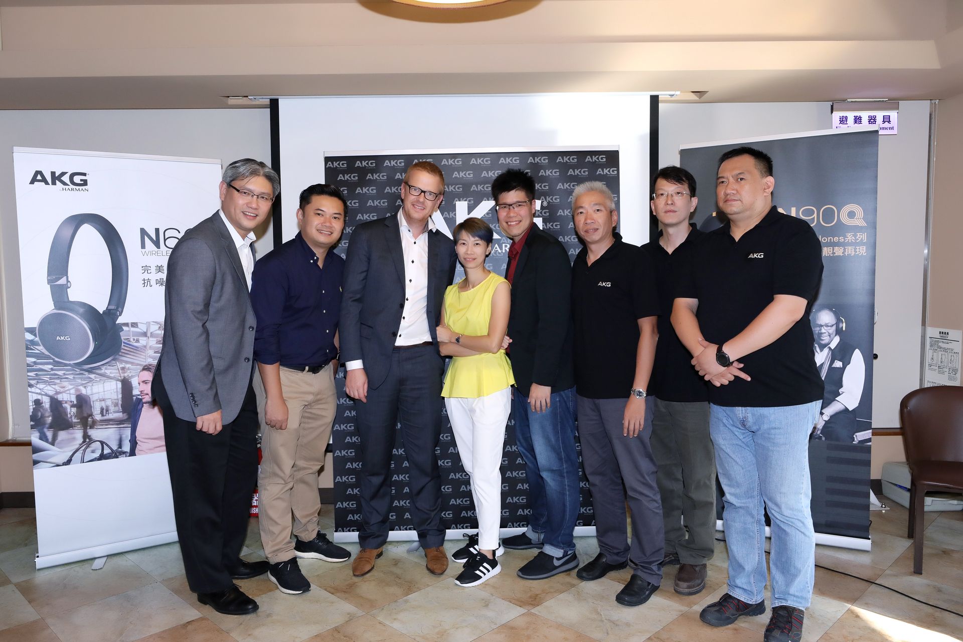 Group of people posing for a photo in front of a backdrop with AKG branding.