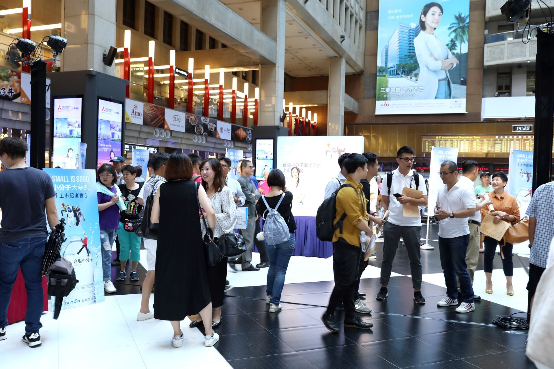 People gather at an indoor event with displays and promotional materials.