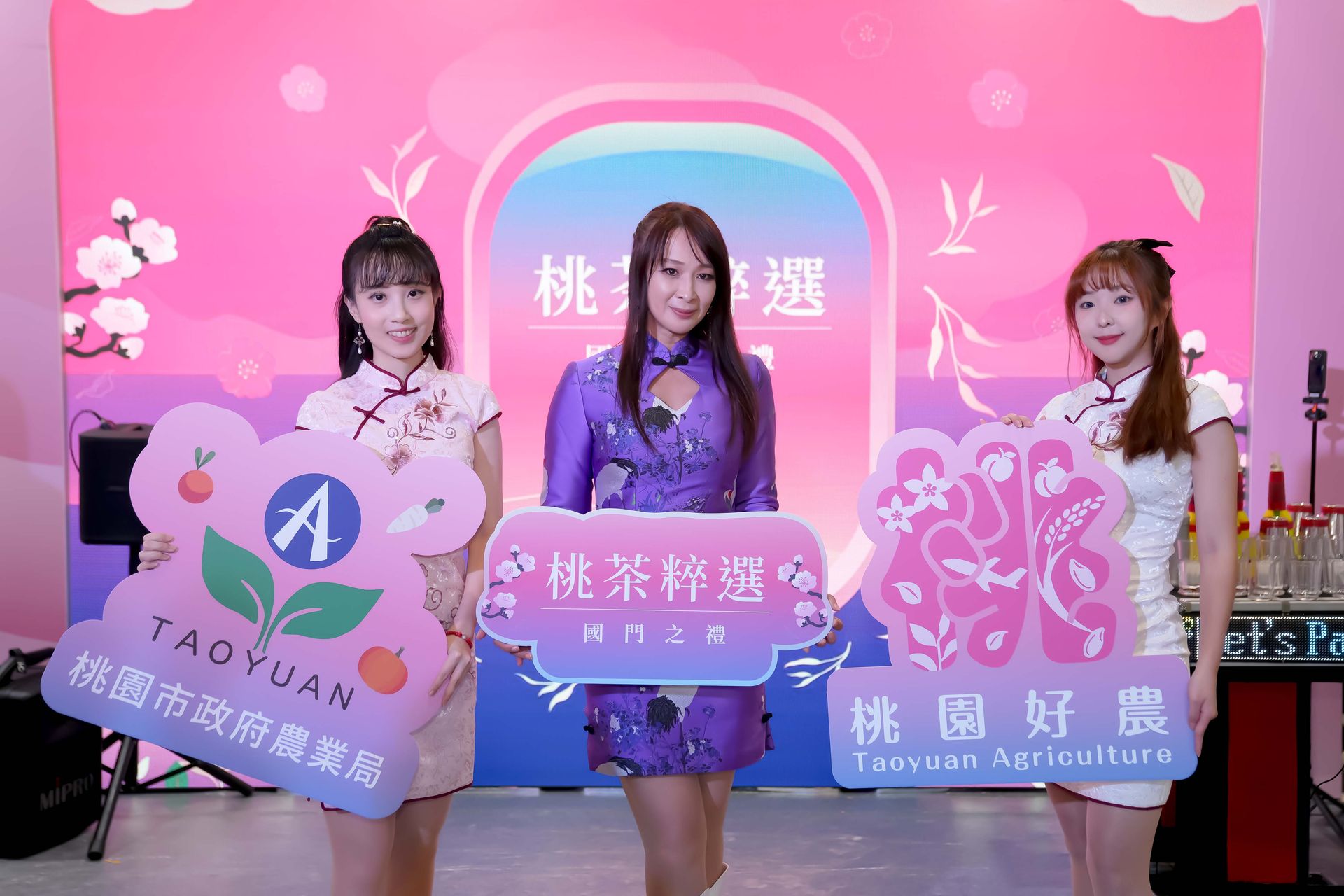 Three women holding signs at a promotional event for Taoyuan agricultural products.