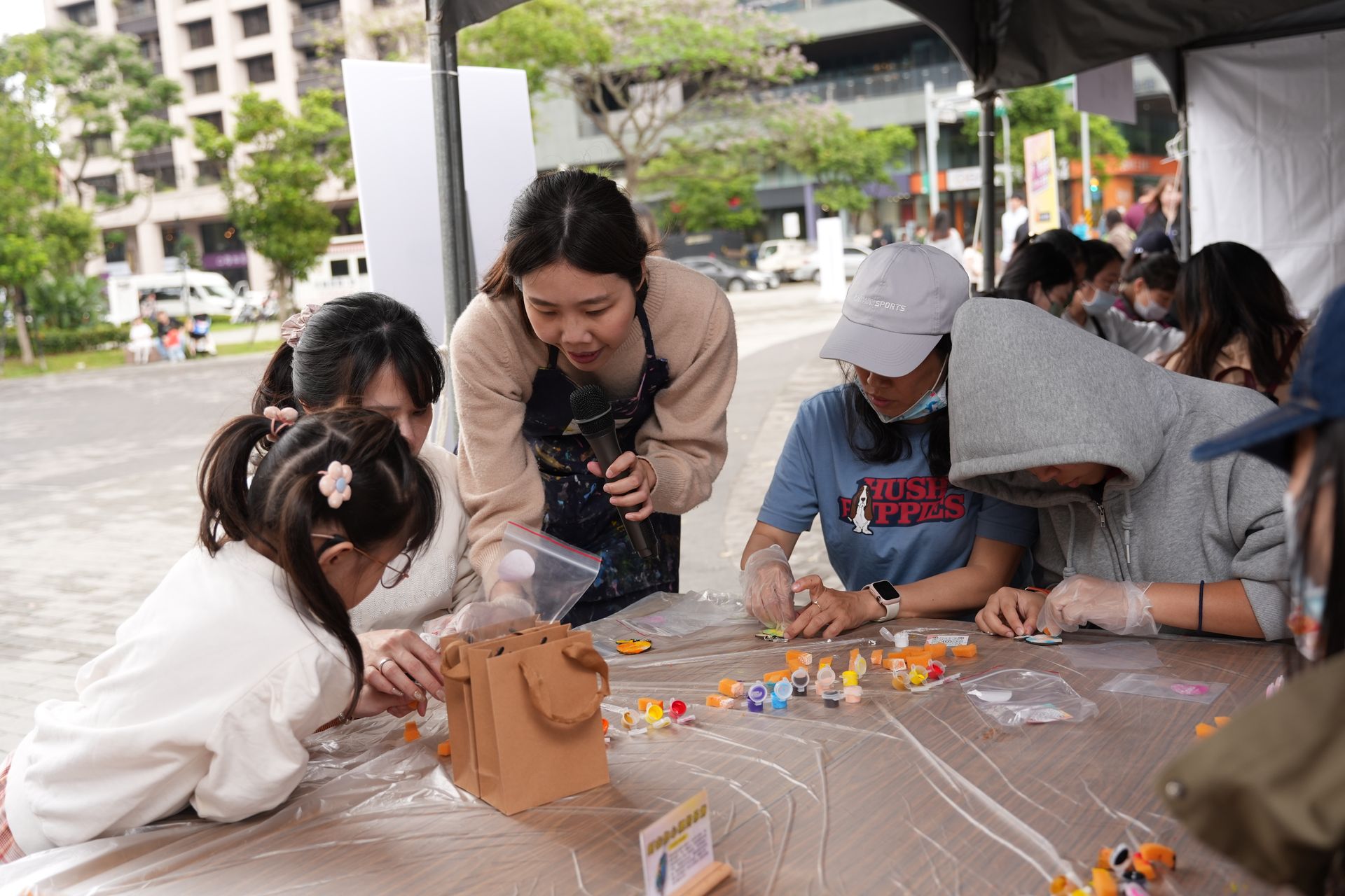People browsing a tea exhibition booth with pink accents, tea product displays, and staff assisting customers.