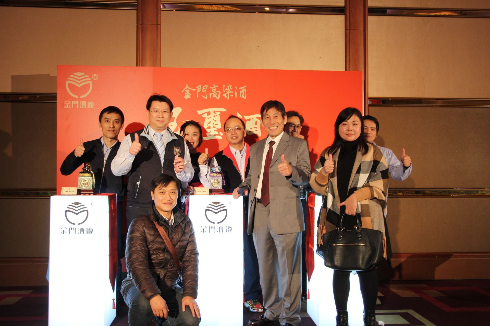 Group of people posing with trophies in front of a red backdrop with Chinese characters and logo.