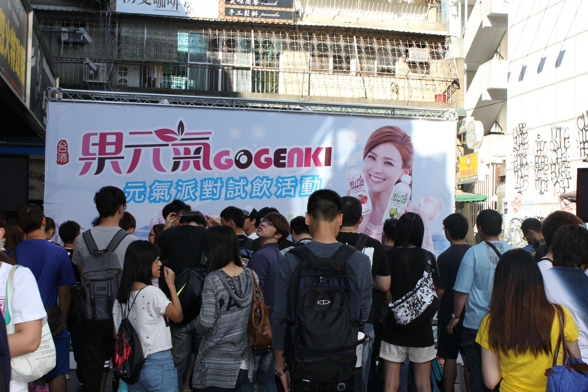 Crowd gathered in front of a banner promoting 