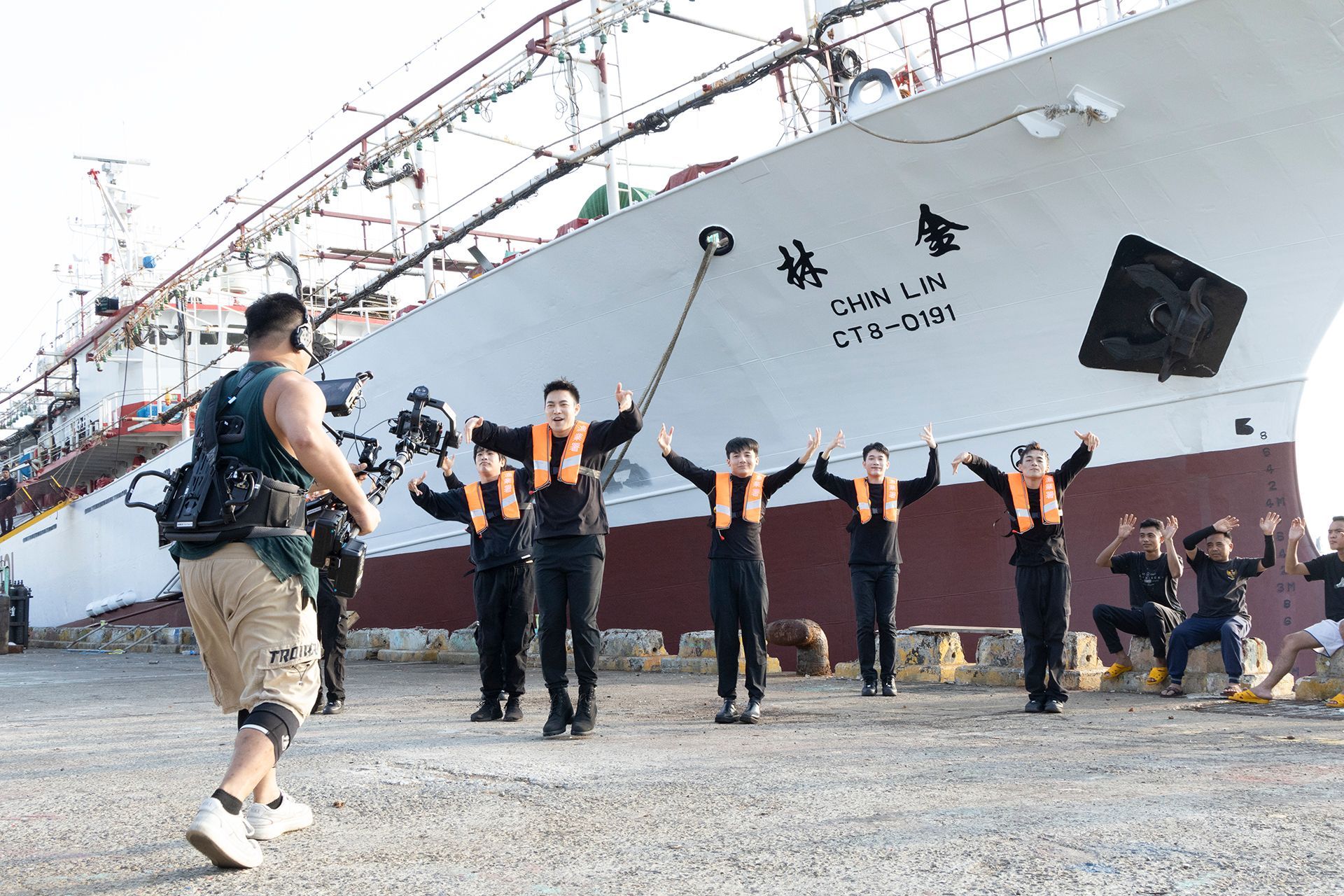 A group of people wearing life vests poses in front of a large white ship.