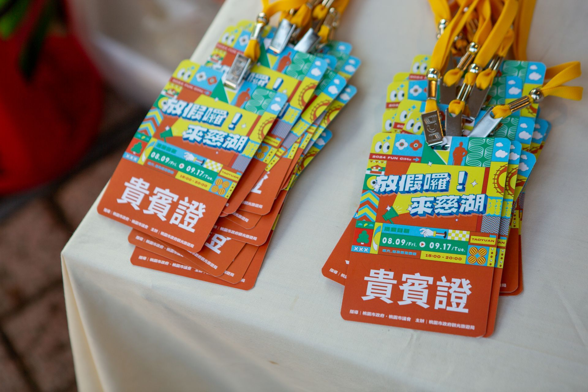 Stacks of orange event badges with yellow lanyards on a table.
