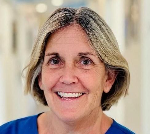 A woman in a blue shirt is smiling for the camera.