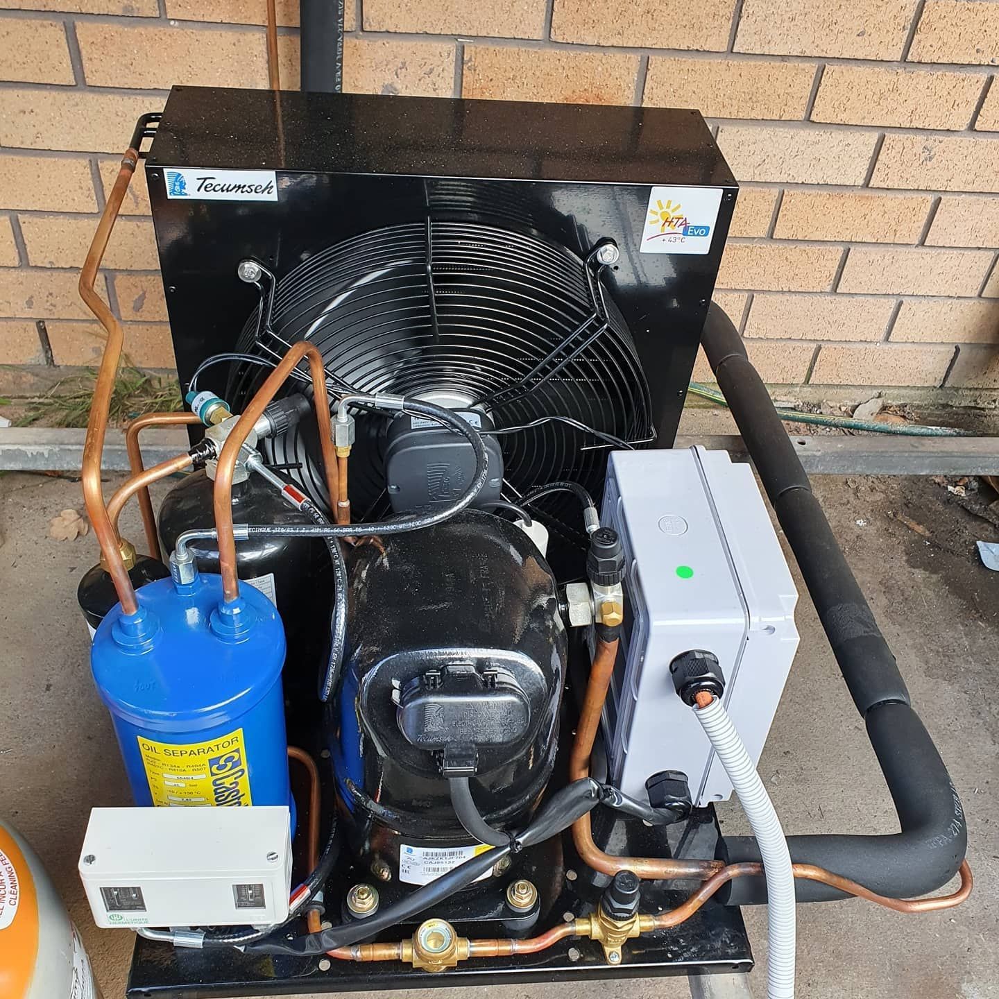 Black refrigeration unit with a blue tank, fan, and copper piping. — Bay & Basin Air Conditioning & Refrigeration Pty Ltd in St Georges Basin, NSW