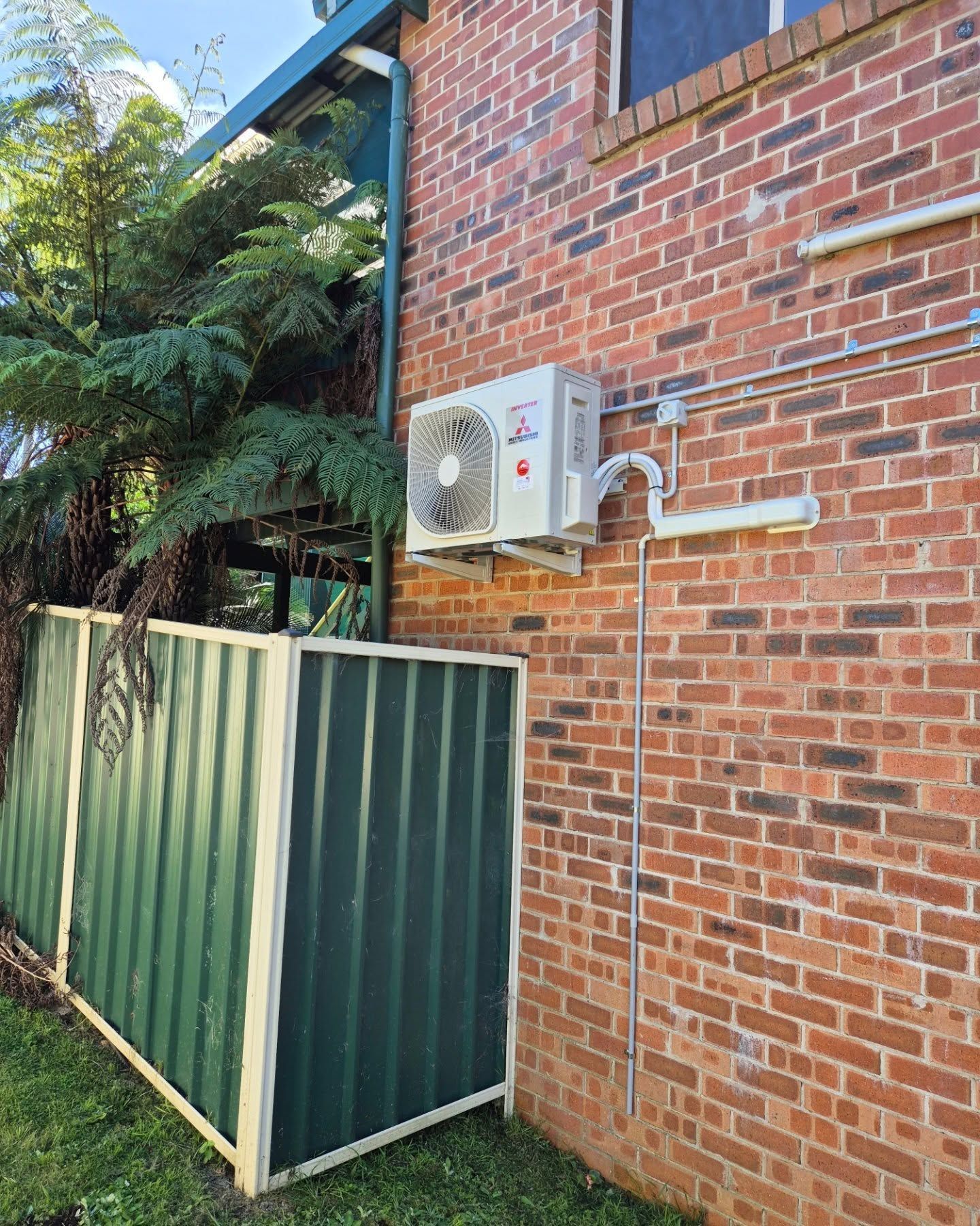 Air Conditioner Unit Mounted on A Red Brick Wall — Bay & Basin Air Conditioning & Refrigeration Pty Ltd in Ulladulla, NSW