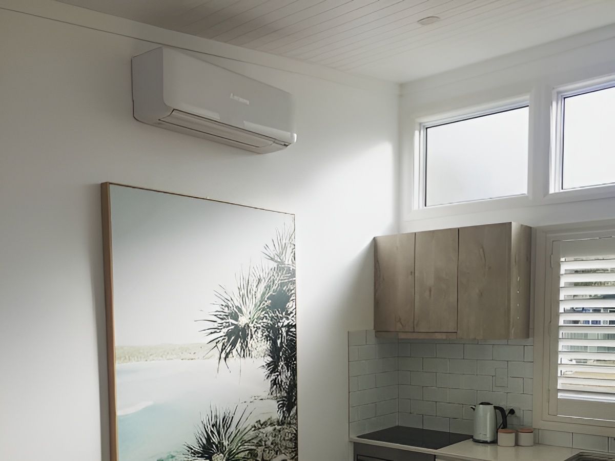 Air conditioner above framed artwork and cabinets in a kitchen. — Bay & Basin Air Conditioning & Refrigeration Pty Ltd in St Georges Basin, NSW