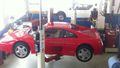 Une voiture de sport rouge est assise sur un ascenseur dans un garage.