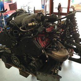 Un moteur de voiture est posé sur une palette en bois dans un garage.