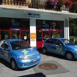 Deux voitures bleues sont garées devant un immeuble.