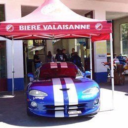 Une vipère d'esquive bleue est garée sous une tente rouge.