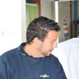 Un homme barbu porte un pull bleu.
