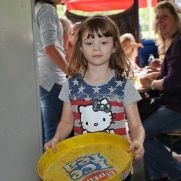 Une petite fille portant une chemise Hello Kitty tient un plateau jaune.