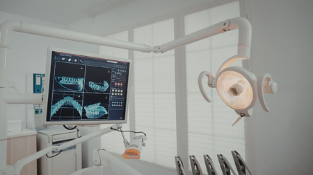 Dental operatory featuring a diagnostic monitor displaying dental X-rays next to an adjustable examination light.