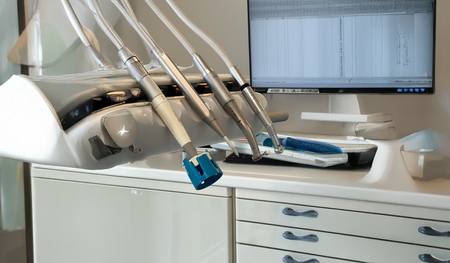A modern dental office station featuring a monitor, dental tools, and storage drawers.