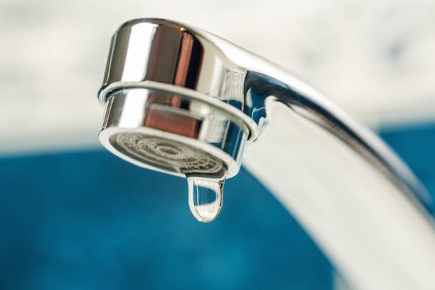 A close up of a faucet with water dripping from it.