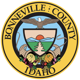 Bonneville County, Idaho seal: Eagle above a shield with a sunset, river, and harvest cornucopias.