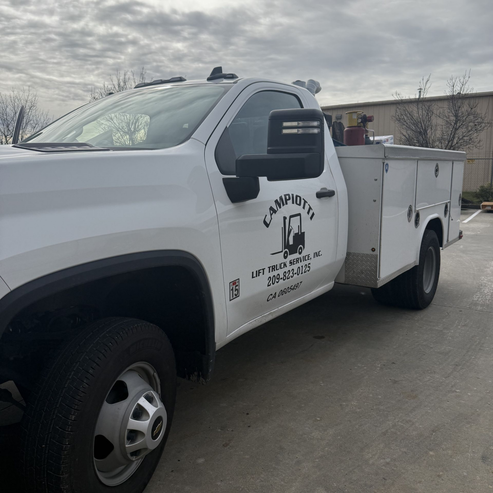 White utility truck with company logo parked outdoors on a cloudy day