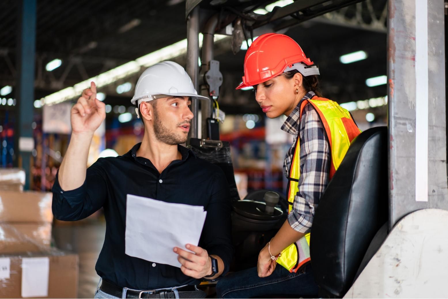 Two construction workers in hard hats discussing plans at a worksite