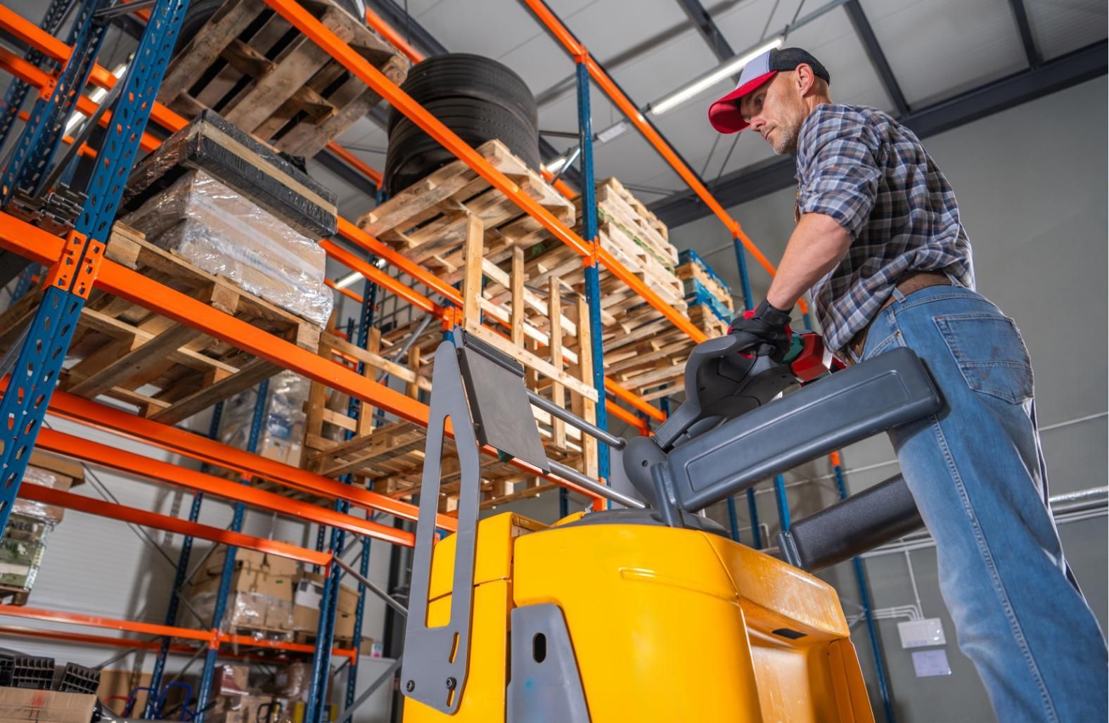 Warehouse worker operating a yellow forklift in an industrial storage aisle