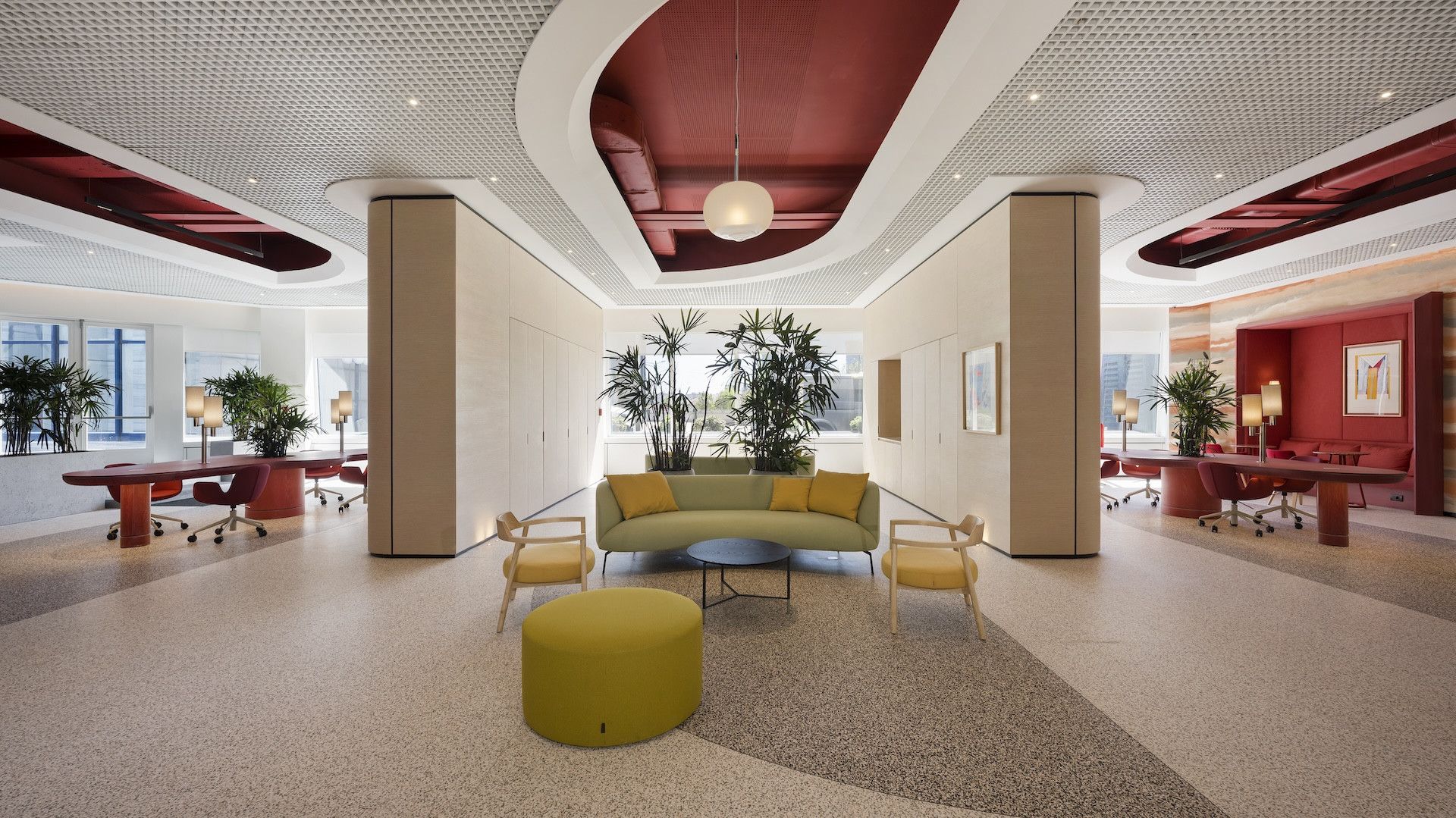 Modern lobby with curved red ceiling, cream columns, patterned floor, and yellow seating area